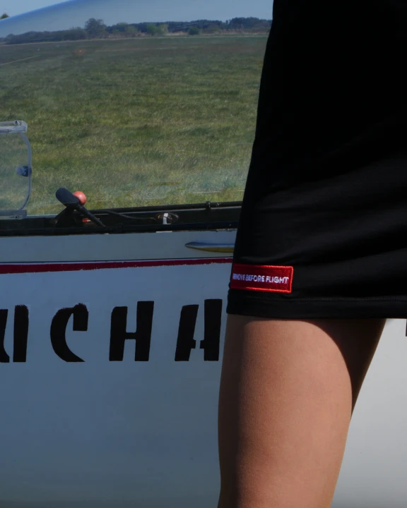 Dopasowana czarna sukienka bawełniana z lotniczymi detalami inspirowanymi awiacją. Haftowane skrzydła pilota, napis „REMOVE BEFORE FLIGHT” i motyw samolotu tworzą unikalny streetwearowy design. Komfortowa, elastyczna i idealna na co dzień.